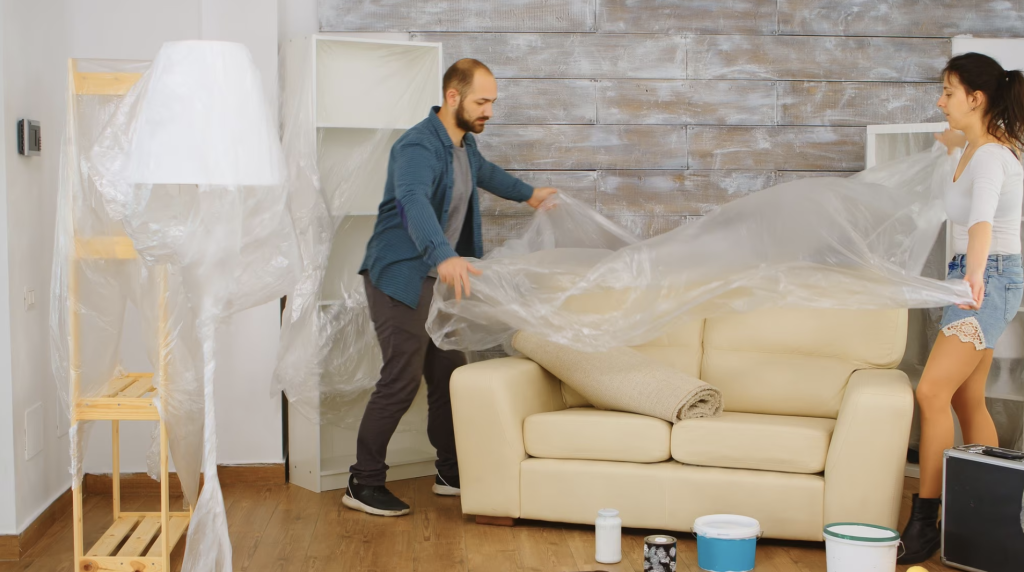 couple wrapping sofa plastic foil protection while they are moving interstate at Melbourne