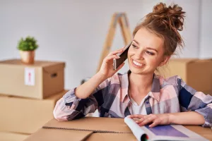 happy woman talking by mobile phone among boxes at Melbourne